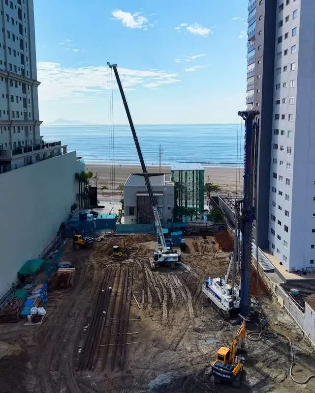 Canteiro de obras do Senna Tower na beira-mar de Balneário Camboriú, com guindaste e o mar ao fundo